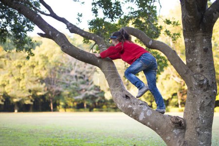 Photo for Cute little asian girl  climbing tree in park - Royalty Free Image