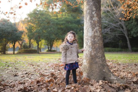 Téléchargez les photos : Petite fille jouant dans la forêt d'automne - en image libre de droit