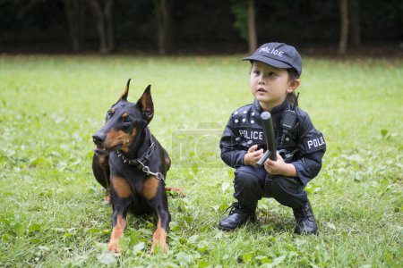 Téléchargez les photos : Fille portant un costume de police faisant une patrouille avec un doberman - en image libre de droit