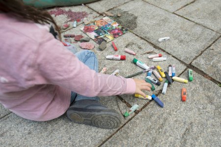 Téléchargez les photos : Fille peinture avec des couleurs sur le trottoir de pierre - en image libre de droit