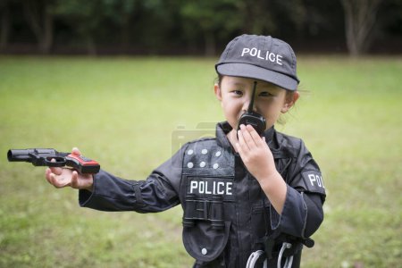 Photo for Little girl wearing a police costume speak in radio - Royalty Free Image