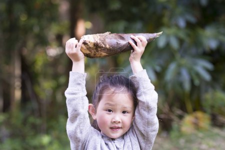 Téléchargez les photos : Petite fille qui a trouvé pousse de bambou - en image libre de droit