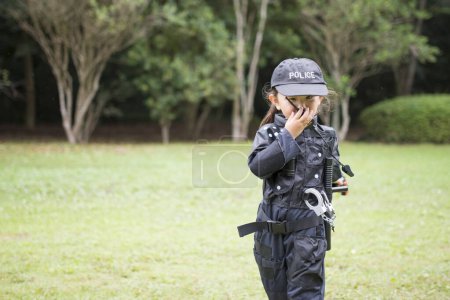 Téléchargez les photos : Petite fille portant un costume de police parler à la radio - en image libre de droit