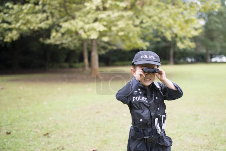 Téléchargez les photos : Petite fille portant un costume de police à surveiller avec des jumelles - en image libre de droit