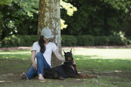 Photo for Woman relax with the Doberman under a tree - Royalty Free Image