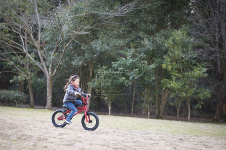 Téléchargez les photos : Asiatique fille équitation vélo sur la route dans les bois. - en image libre de droit