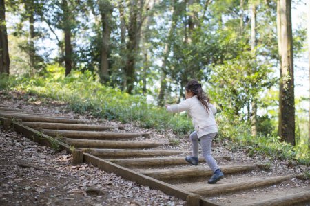 Téléchargez les photos : Mignonne petite fille asiatique courir dans une forêt - en image libre de droit