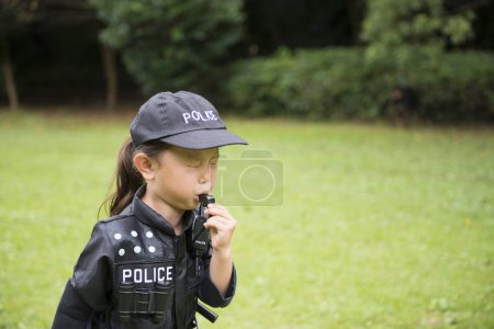 Photo for Little girl wearing a police costume blowing the whistle - Royalty Free Image