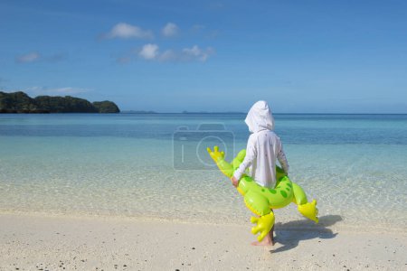 Téléchargez les photos : Heureuse petite fille jouer sur la plage - en image libre de droit