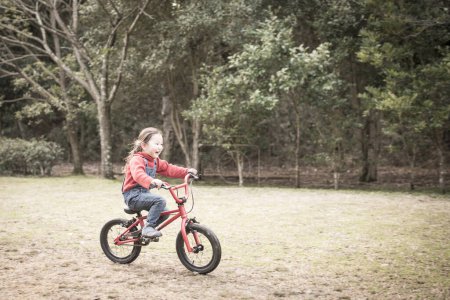 Téléchargez les photos : Petite fille en vélo dans une forêt - en image libre de droit