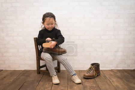 Foto de Lindo niño pequeño limpieza de sus botas - Imagen libre de derechos