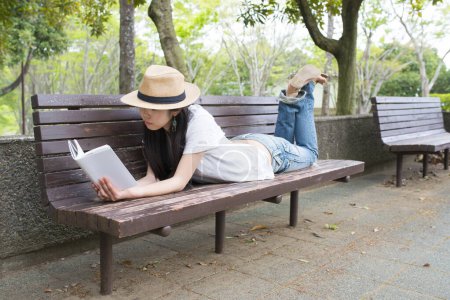 Téléchargez les photos : Femme lisant un livre sur banc - en image libre de droit