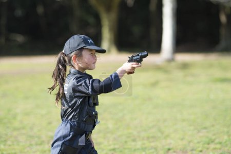 Photo for Little girl with a toy pistol wearing a police costume - Royalty Free Image