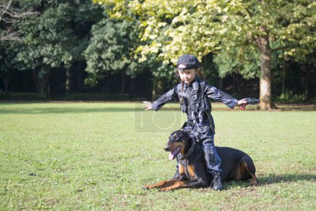 Photo for Girl wearing a police costume going on a patrol with a doberman - Royalty Free Image