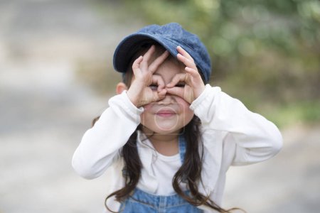 Photo for Asian little girl making glasses gesture - Royalty Free Image