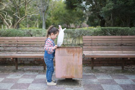 Téléchargez les photos : Fille à jeter les ordures dans la poubelle - en image libre de droit