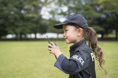 Téléchargez les photos : Petite fille portant un costume de police parler à la radio - en image libre de droit