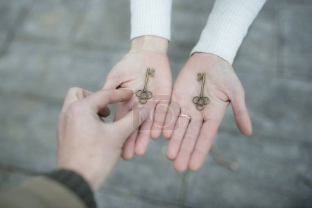 Téléchargez les photos : Les mains de l'homme et de la femme remettant les clés - en image libre de droit