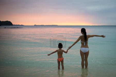 Foto de Madre e hija jugando al atardecer en la playa - Imagen libre de derechos