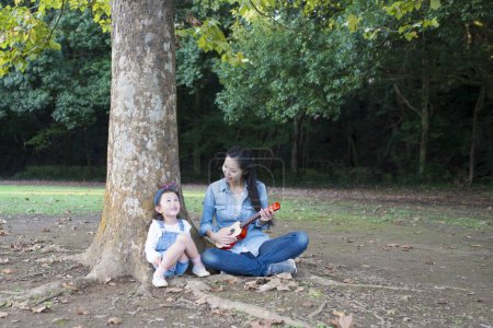 Téléchargez les photos : Mère et fille chantent et jouent de la guitare dans le parc - en image libre de droit