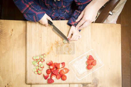 Photo for Girl cutting strawberries on board - Royalty Free Image