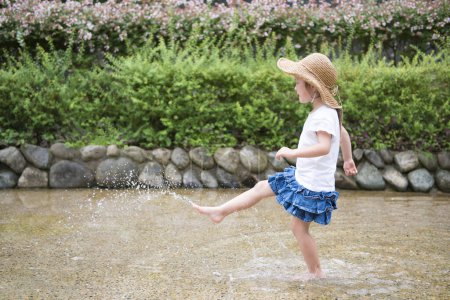 Photo for Young girl in a hat walking in river  in the park - Royalty Free Image