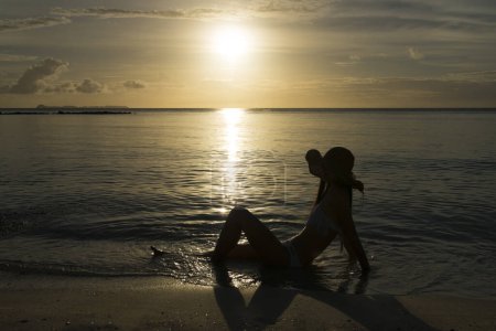 Foto de Hermosa silueta de mujer relajante en la playa del atardecer - Imagen libre de derechos