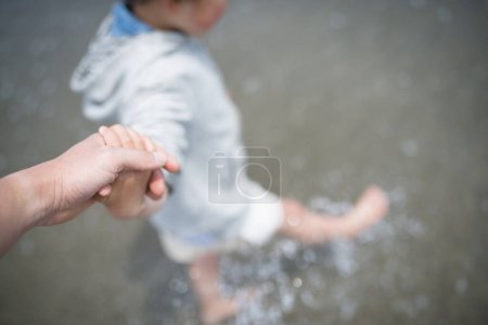 Parent and child holding hands at the beach
