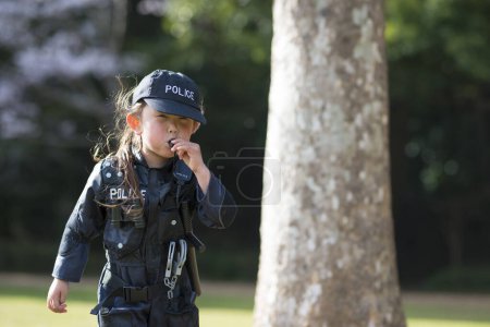 Photo for Little girl blowing whistle in police costume - Royalty Free Image
