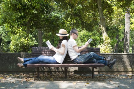 Photo for Couple read a books on bench - Royalty Free Image
