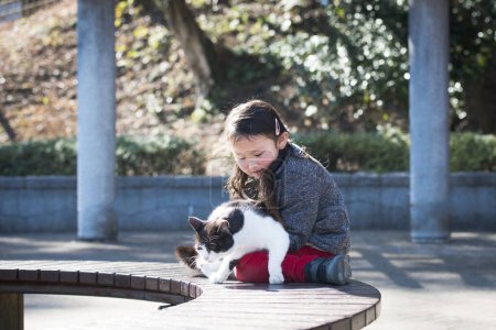 Téléchargez les photos : Mignonne petite fille asiatique avec chat dans le jardin - en image libre de droit