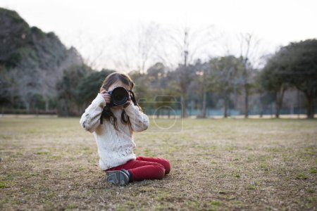 Photo for Young girl taking photos in park - Royalty Free Image