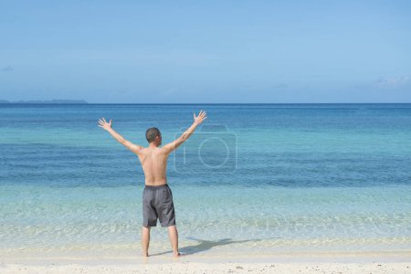 Téléchargez les photos : Homme levant les mains à la plage - en image libre de droit