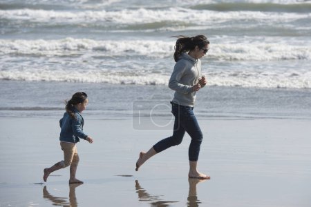 Téléchargez les photos : Mère et fille jouent sur la plage - en image libre de droit