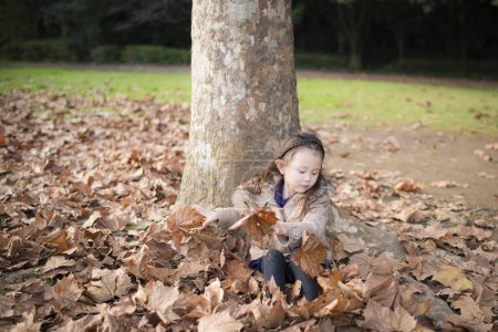 Téléchargez les photos : Petite fille jouant dans la forêt d'automne - en image libre de droit