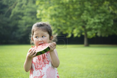 Téléchargez les photos : Asiatique fille manger pastèque dans parc - en image libre de droit
