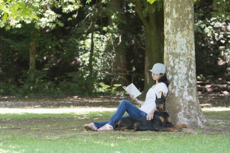 Foto de La mujer leyó un libro con el doberman - Imagen libre de derechos