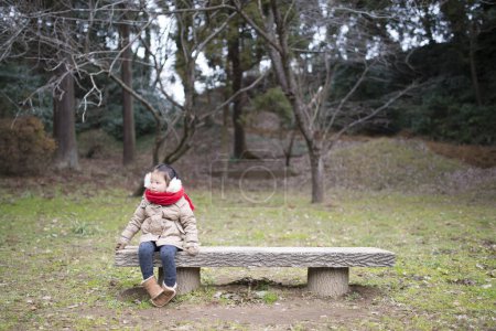 Téléchargez les photos : Fille assise sur le banc dans le parc - en image libre de droit