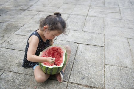 Téléchargez les photos : Mignonne petite fille manger pastèque en plein air - en image libre de droit