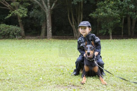 Girl wearing a police costume going on a patrol with a doberman