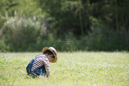Photo for Girl picking flowers in field - Royalty Free Image