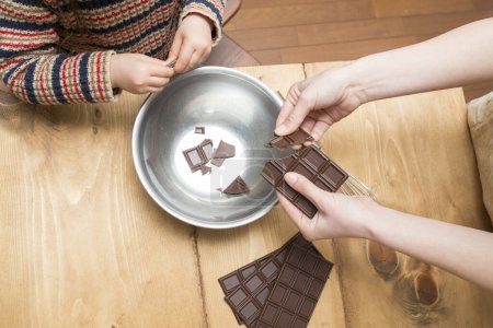 Photo for Mother and daughter breaking chocolate - Royalty Free Image