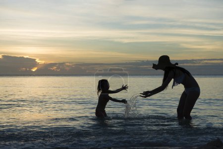 Foto de Madre e hija silueta jugando en la playa del atardecer - Imagen libre de derechos