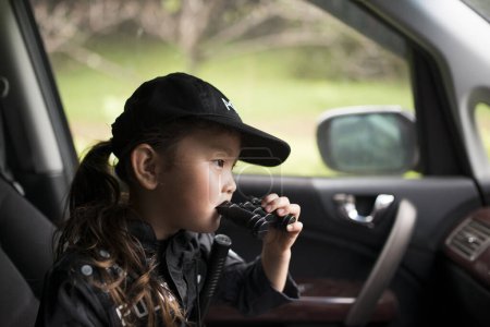 Téléchargez les photos : Fille portant un costume de police surveillance dans la voiture - en image libre de droit