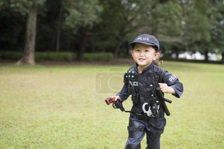 Chica usando un disfraz de policía corriendo en el césped