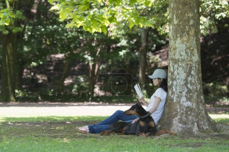 Téléchargez les photos : Femme a lu un livre avec le doberman - en image libre de droit