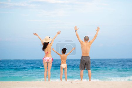 Father and mother and daughter to raise both hands at the beach