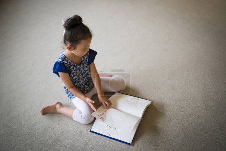 Photo for Asian little girl reading a book - Royalty Free Image