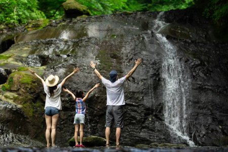 Father, mother and daughter playing in the mountain stream