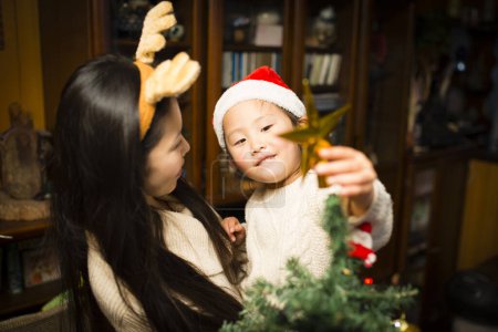 Téléchargez les photos : Mère et fille décorant l'arbre de Noël - en image libre de droit